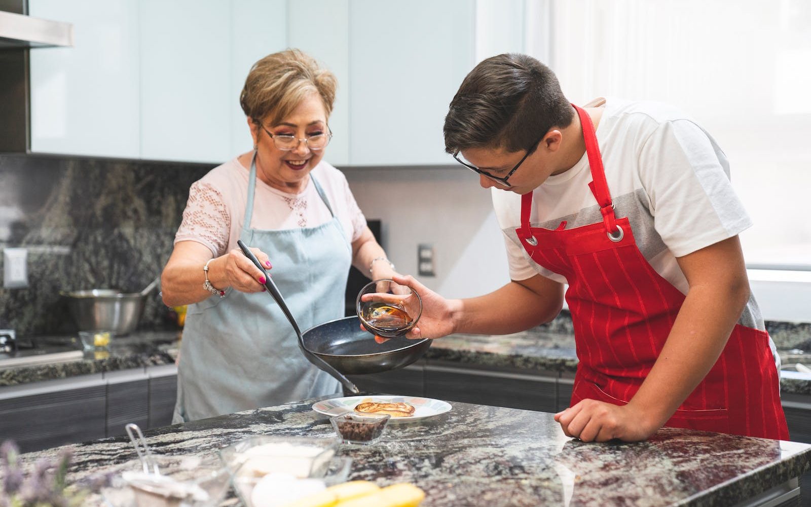 Woman and Man Wearing Aprons Preparing Food in a Kitchen