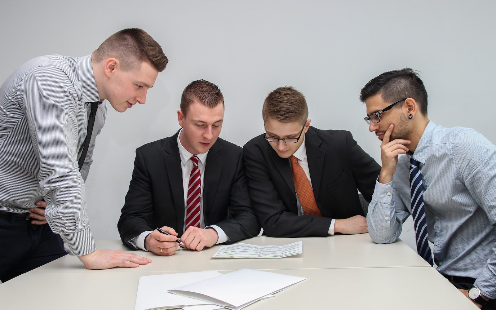 four men looking to the paper on table