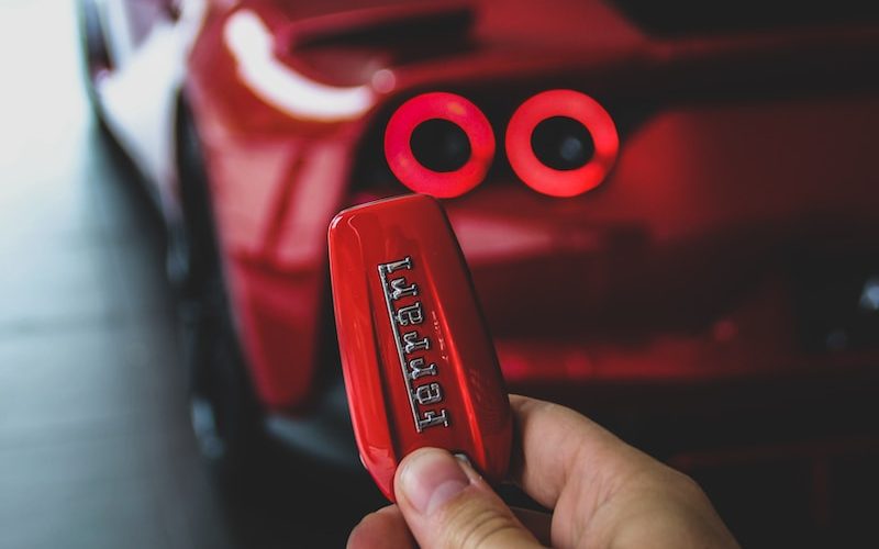 red person with keyfob of red Ferrari supercar