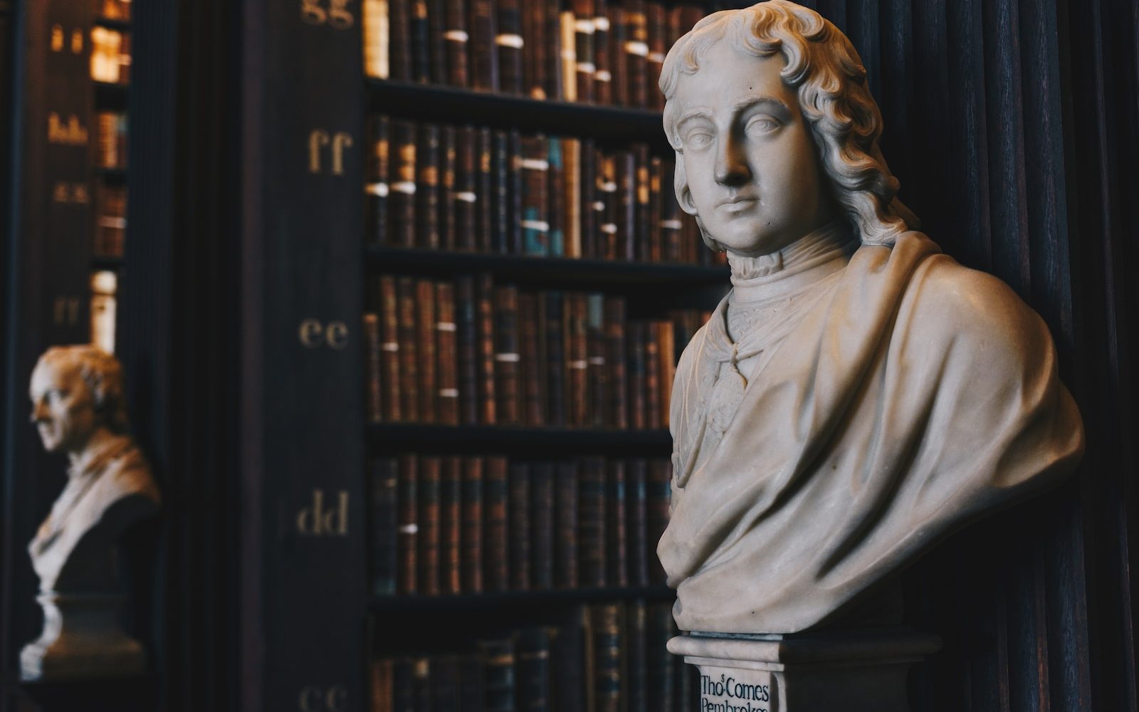 man wearing robe bust figurine near black wall