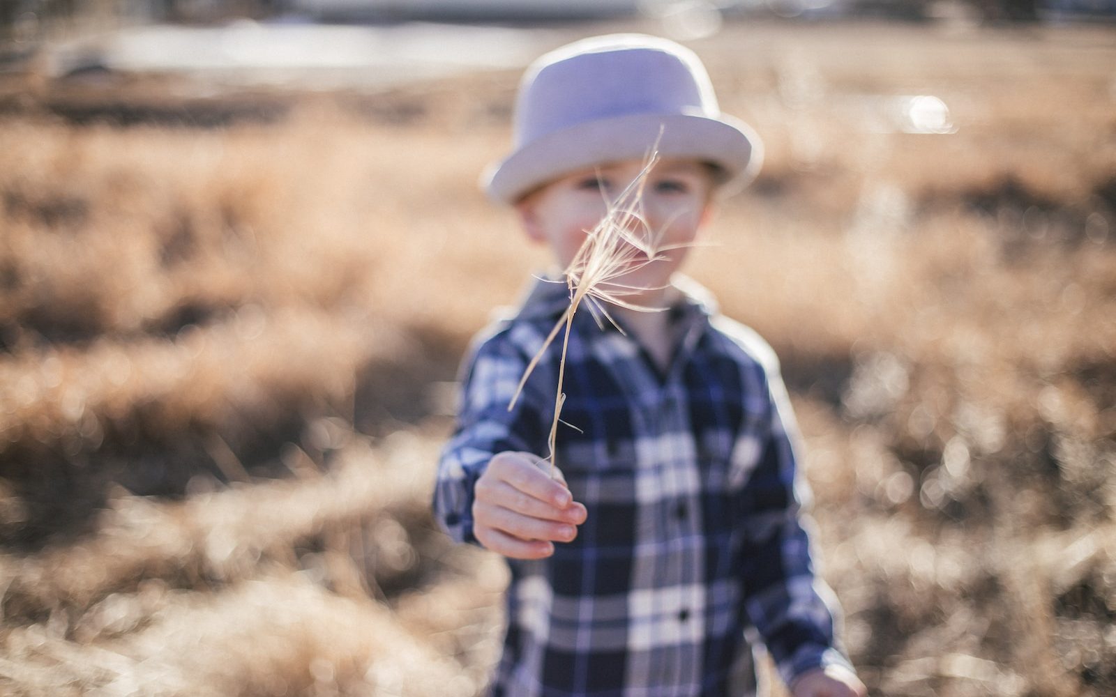 selective focus photography of boy standing near outdoor during daytime