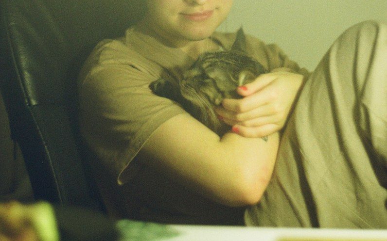 woman sitting on chair while carrying cat