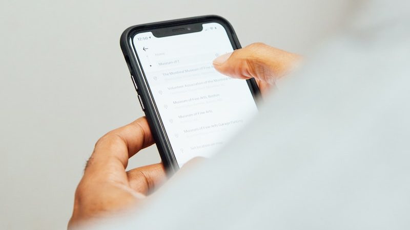 man in white top holding iPhone