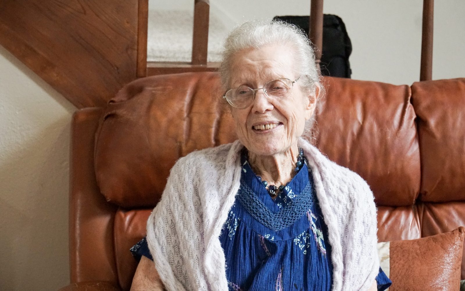 woman in blue shirt and gray cardigan sitting on brown sofa