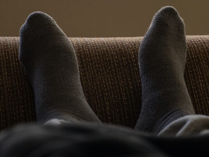 person in gray pants lying on brown textile